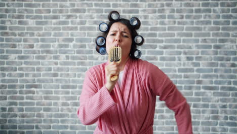 woman singing in bathrobe with hair rollers and microphone