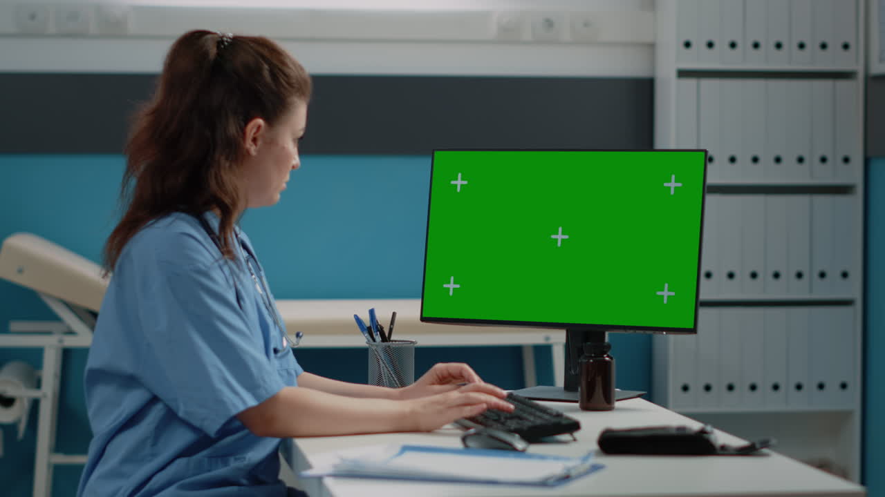 Doctor working on a computer with a green screen in a medical office