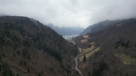 Aerial-ascend-along-river-and-road-leading-to-frozen-reservoir-in-distance