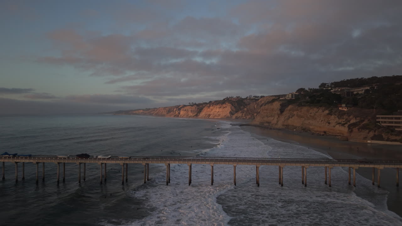 Drone aerial of Scripps Pier at sunset in La Jolla, San Diego, drone flyover at sunset