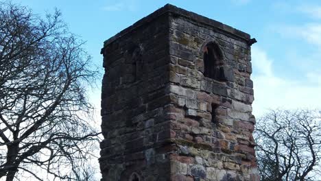 Looking-up-at-Windleshaw-Chantry-stonework-tower-exterior-slow-motion-around-ruins-against-blue-sky