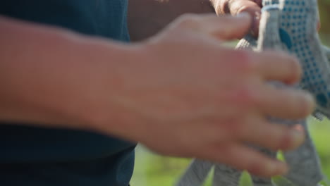 close up fair skinned man removing glove from left hand after outdoor work, soft green background blur, focus on skin texture and careful motion showing end of labor routine