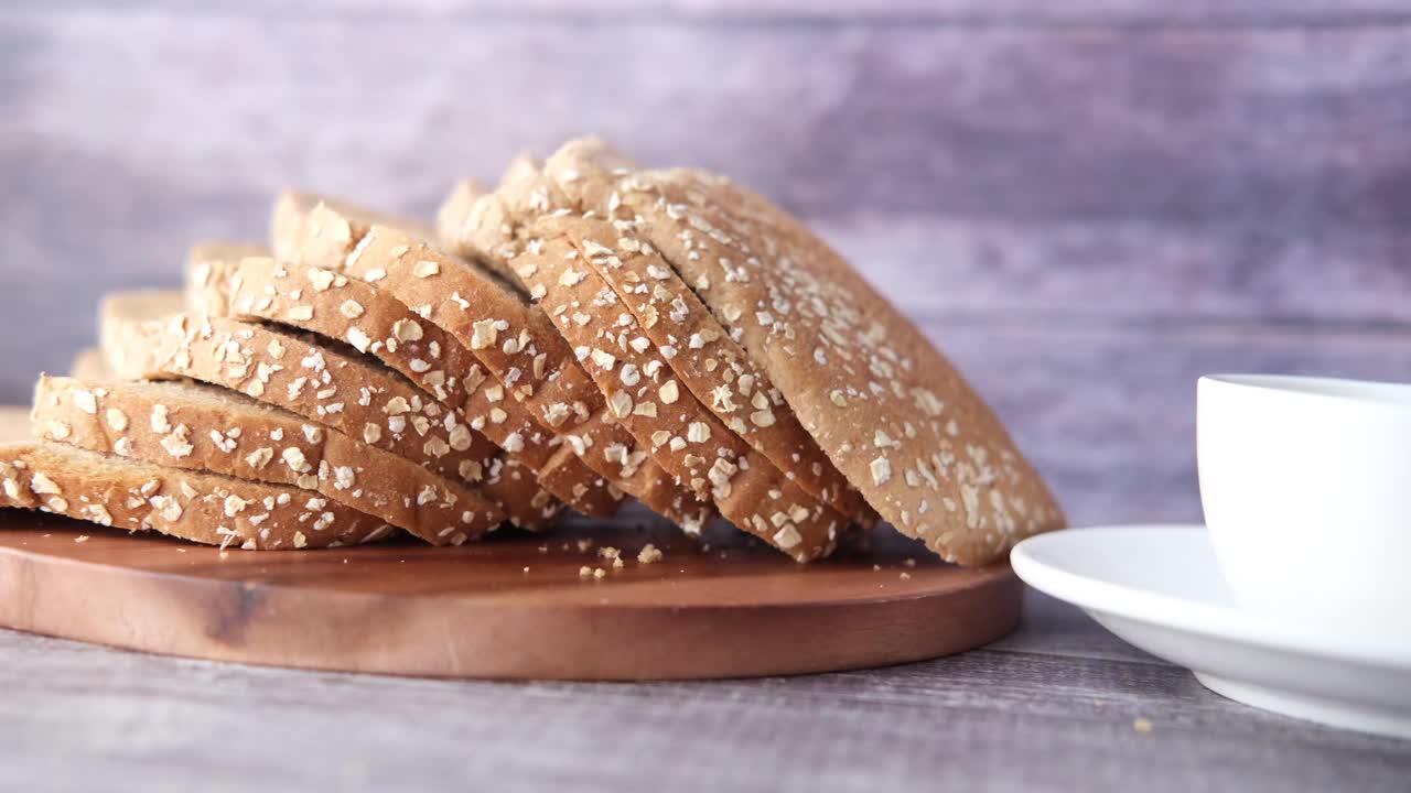 pan de avena cortado en una tabla de cortar de madera con una taza de café