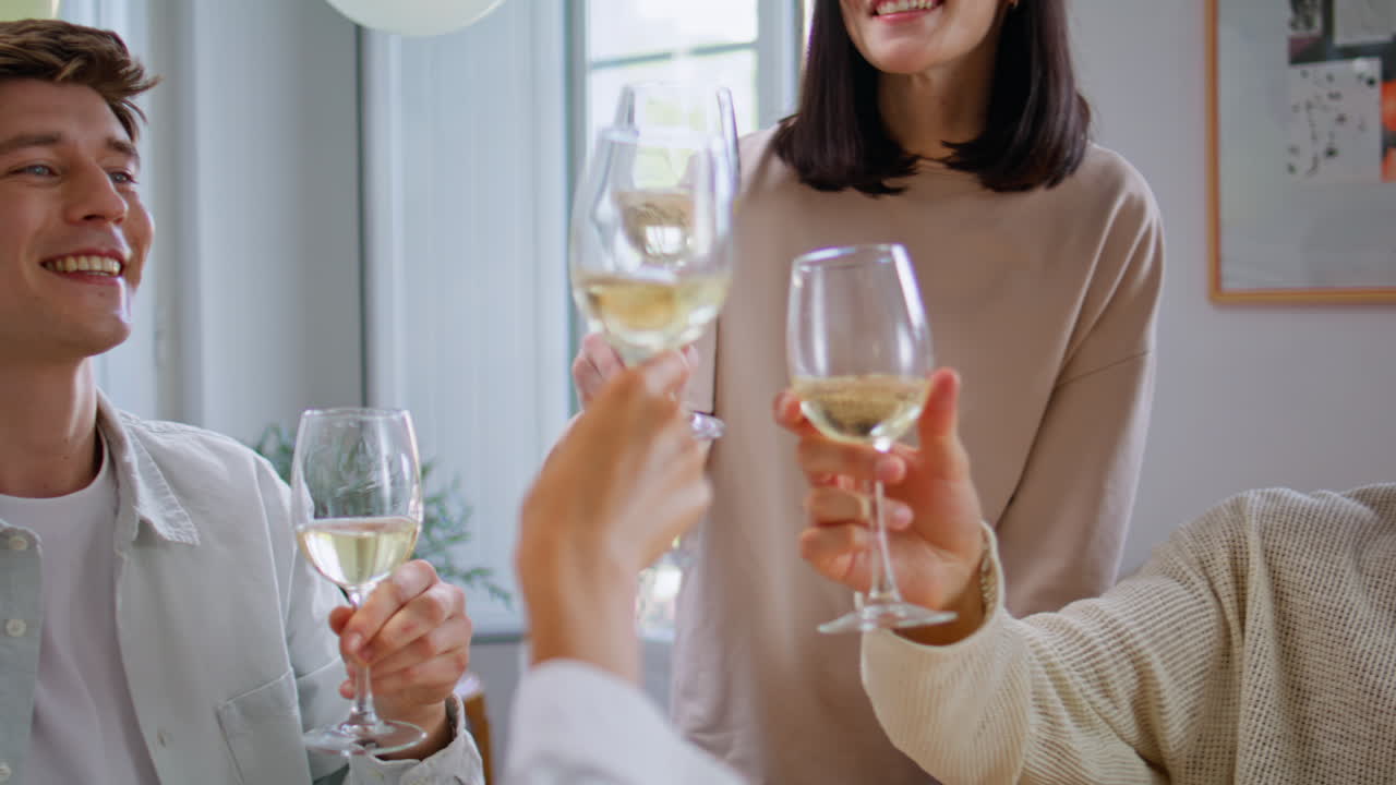 Festive friends clinking wine glasses at birthday party closeup. People toasting