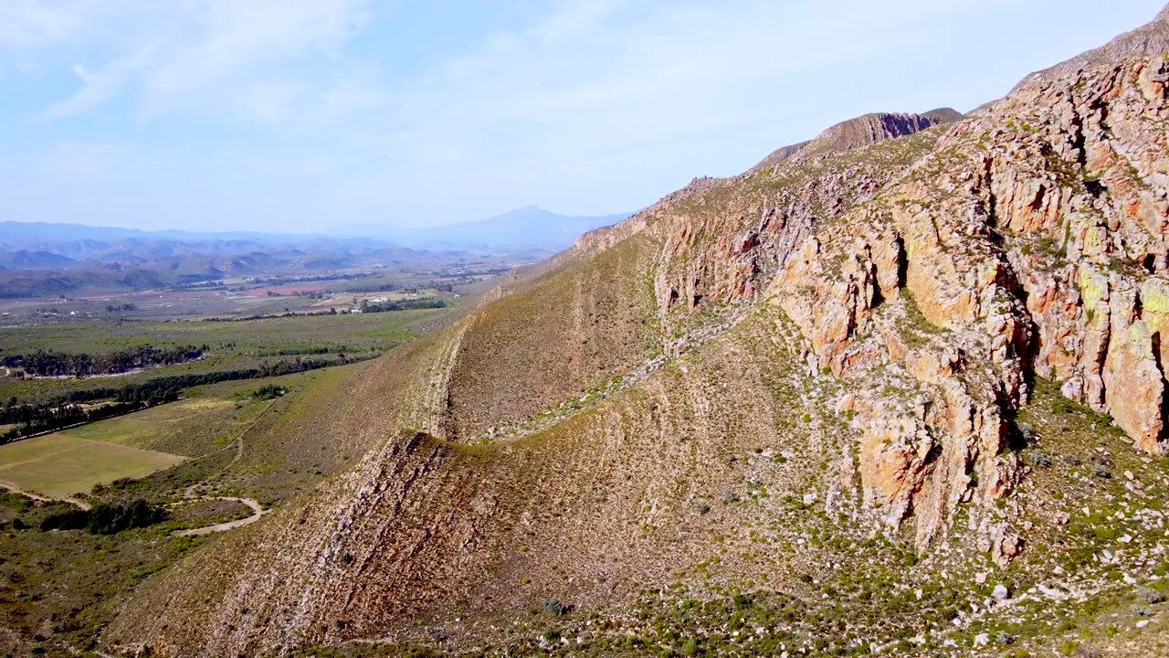 Geología accidentada y formaciones rocosas a lo largo de las laderas de las montañas Langeberg, toma aérea en movimiento.