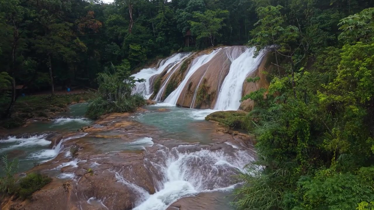 Una vista panoramica grandangolare che cattura l'acqua bianca che scende a cascata impetuosamente su terrazze di travertino calcareo ad Agua Azul, in Chiapas, Messico.