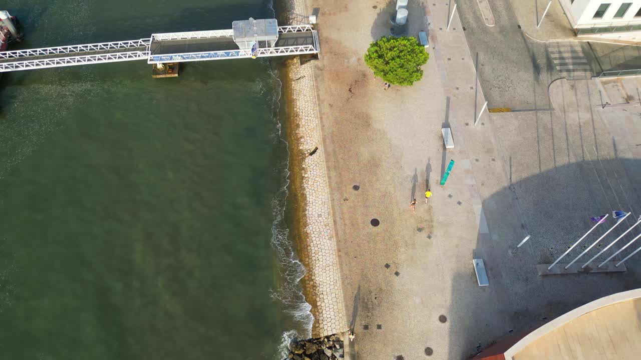 Aerial view from a couple and another runners jogging at Lisbon riverside with their shadows refleting ate the pavement,Portugal