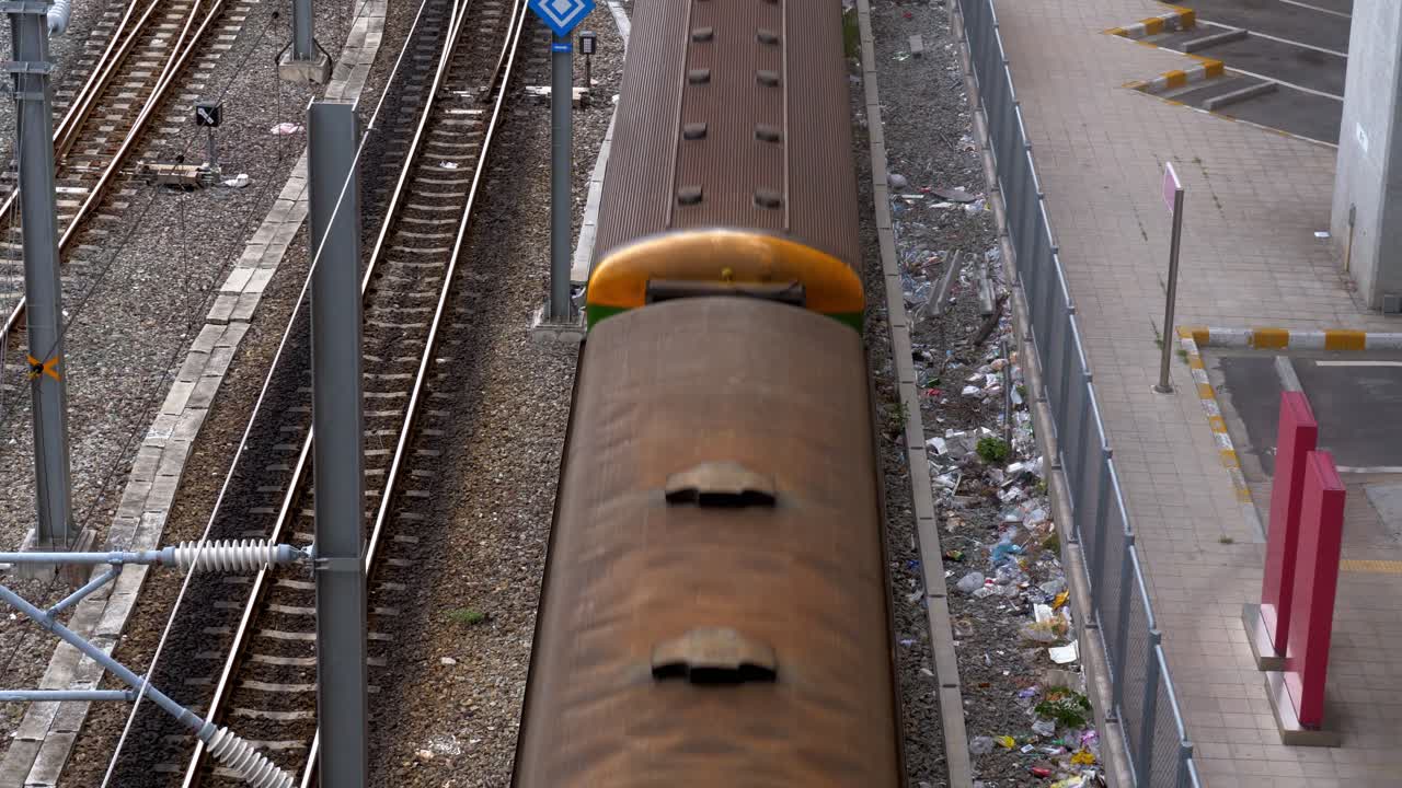 A multi-car train running on a railroad viewed in high angle showing train's roof