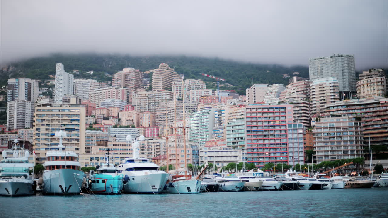 View of boats docked in the Monaco Marina with the skyline of the city on the background