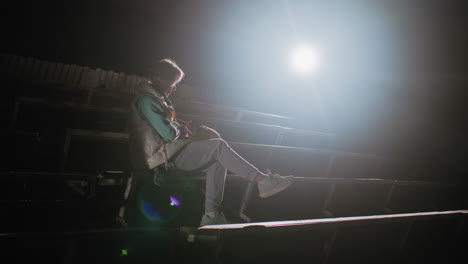 dog owner seated on stadium benches at night carrying pet dog lovingly on her lap under bright spotlight, creating peaceful emotional bond moment showing warmth, tenderness, and companionship