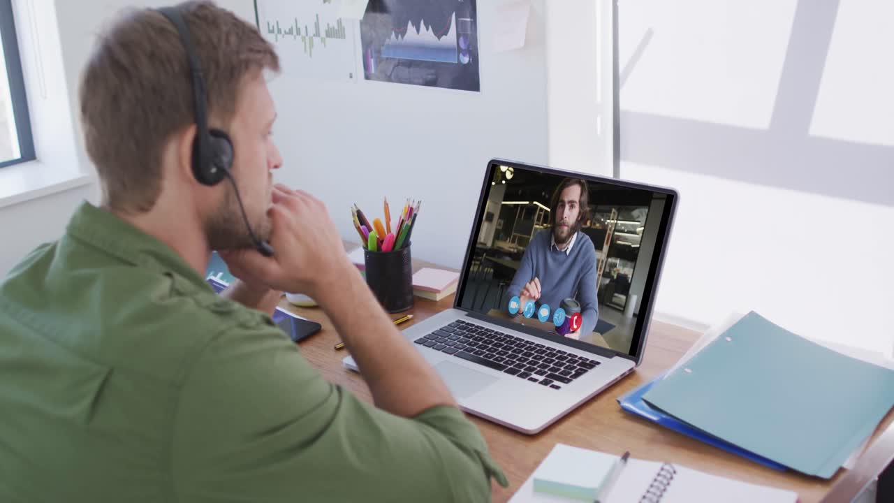 Kaukasisk mand bruger bærbar computer og telefonheadset på videoopkald med en mandlig kollega.