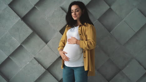 young happy pregnant woman holding and stroking her belly