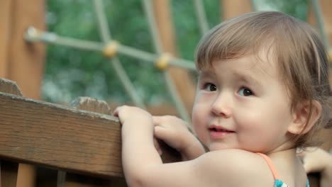 cute adorable kid girl jumping standing by a wooden obstacle course playground - slow motion