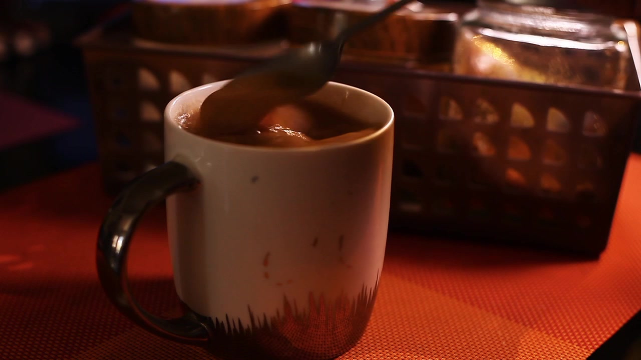 Café caliente en una taza siendo removido con una cucharilla.