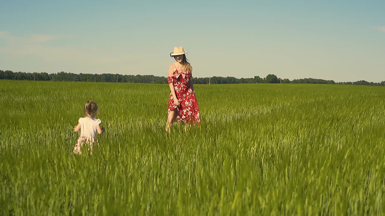 느린 움직임 젊은 어머니는 바람에 날아다니는  ⁇ 은 드레스를 입고  ⁇ 에서 아이와 함께 놀고 있습니다.
