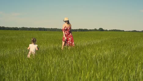 slow motion young mother plays with child in the field dressed in red dress that flutters in the wind 1