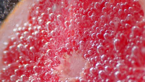 slice of ripe grapefruit under water with air bubbles.