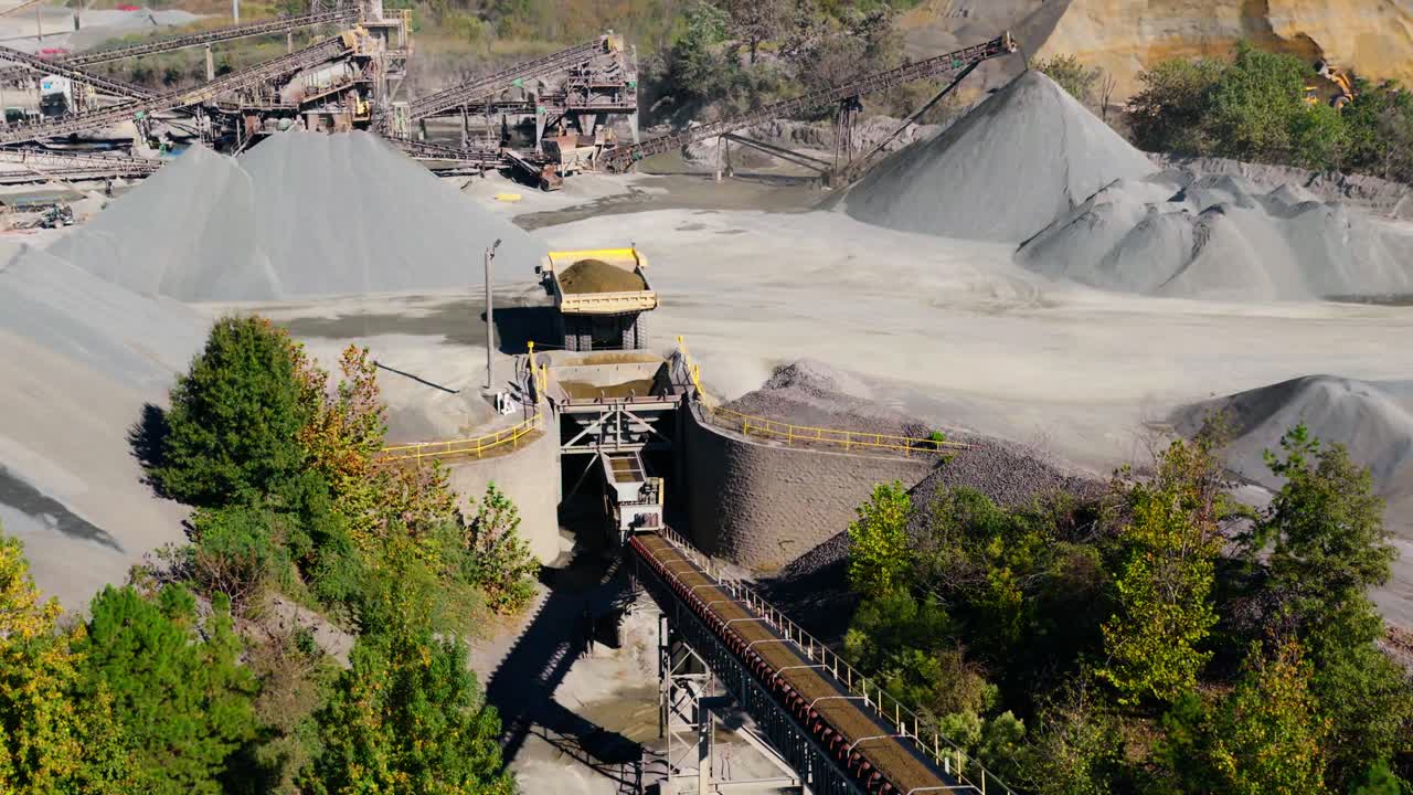 Dump truck unloading gravel into hopper at quarry in Arkansas USA, aerial overview