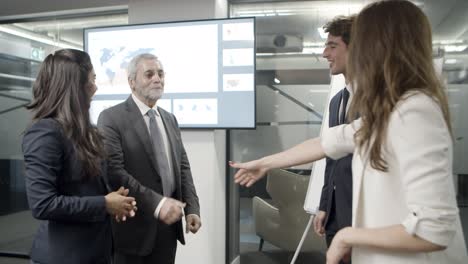 smiling office workers shaking hands in office