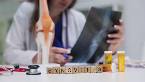 doctor reviews synovitis x-ray with medical model and medication