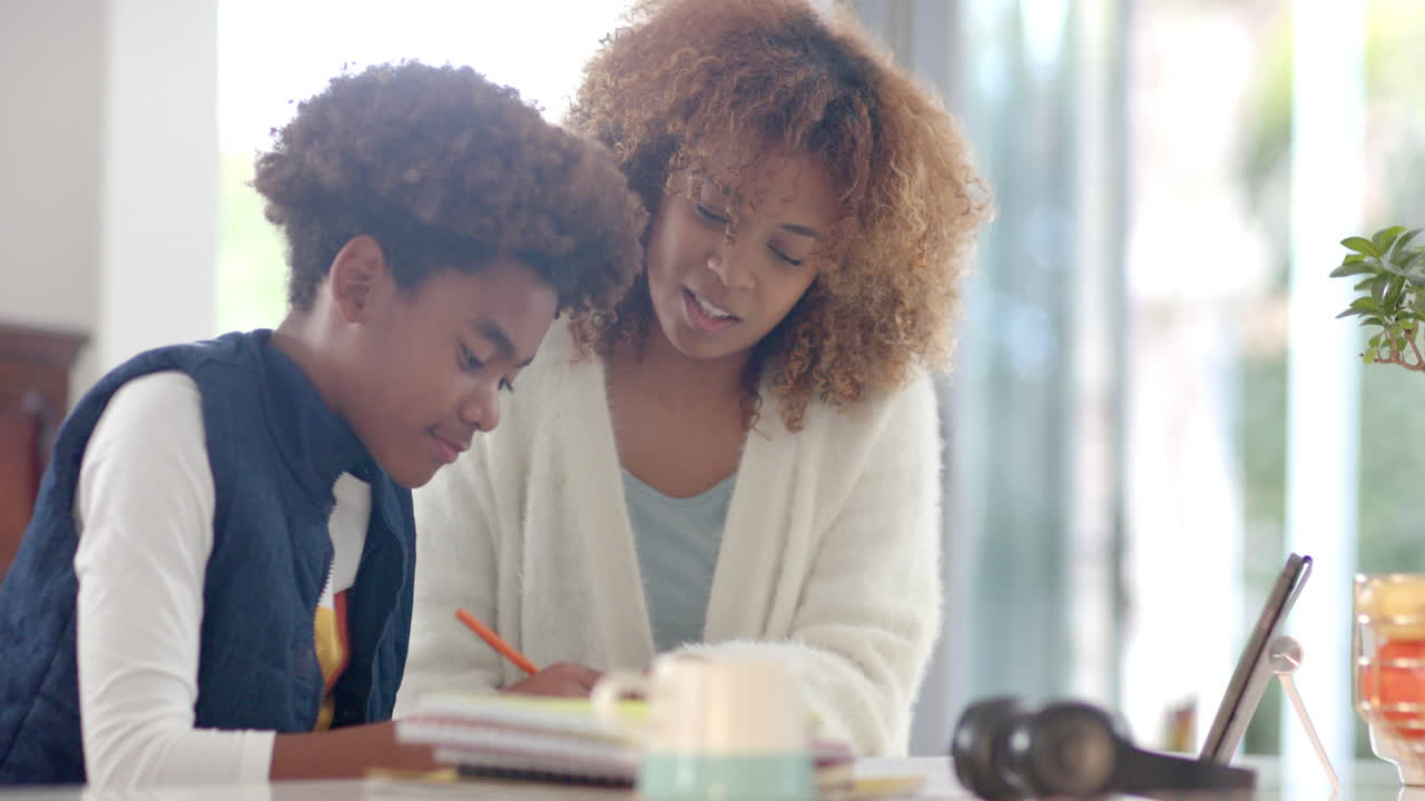 African american mother helping her son with homework, slow motion