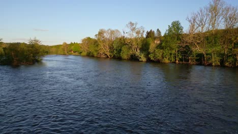 Drone-flying-at-low-altitude-over-Vienne-river-in-Saint-Victurnien-countryside,-Nouvelle-Aquitaine-in-France