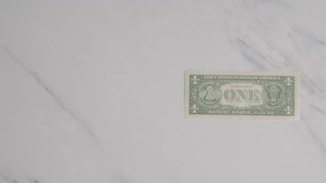 overhead currency shot of hand grabbing us 1 dollar bill on marble surface 1