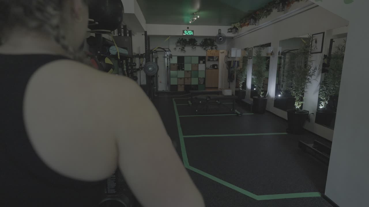 una toma deslizante de una mujer blanca haciendo ejercicio en una bicicleta estática dentro de un gimnasio