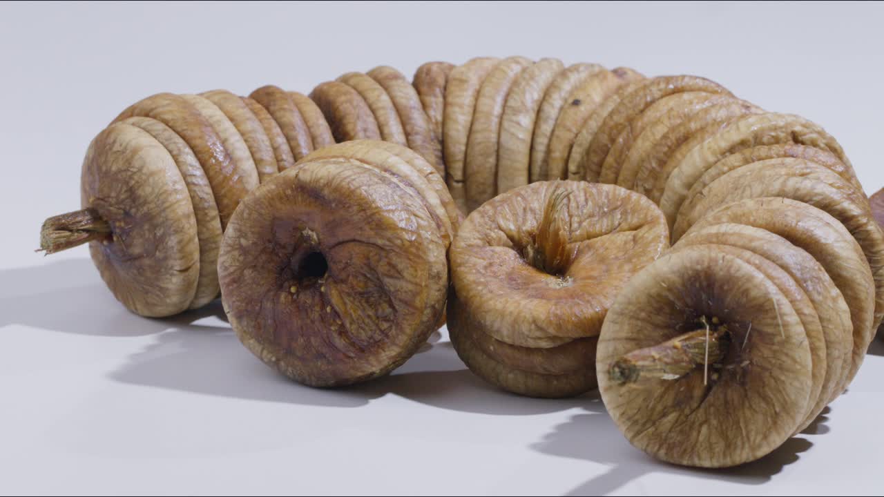 A steady mid close shot of a set of figs kept on a table in a studio set up as a hand comes and picks up one fig.