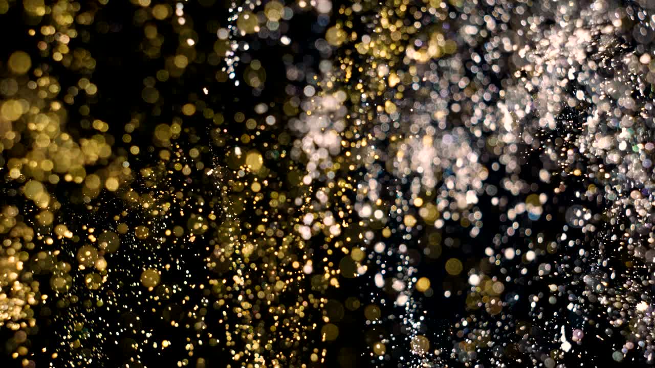 Particelle eleganti, dettagliate e dorate fluiscono con profondità di campo ridotta sott'acqua.