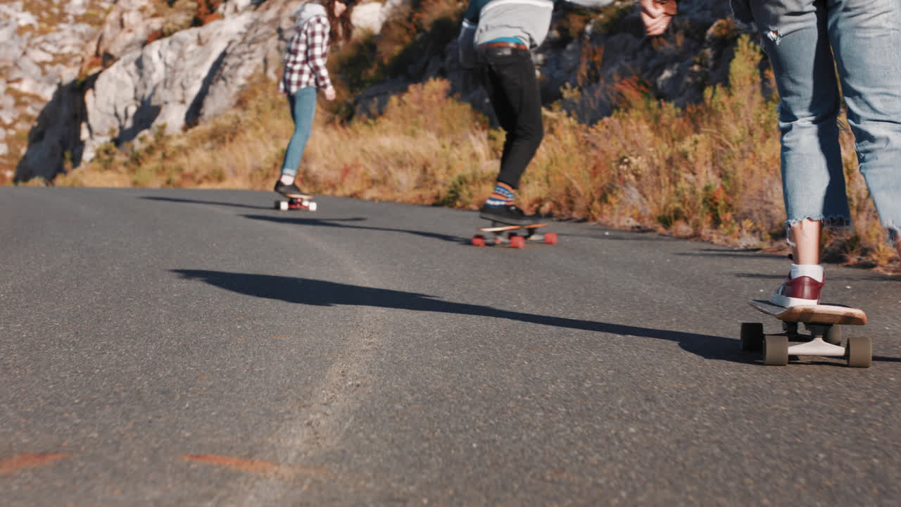 jóvenes amigos multiétnicos longboarding juntos montando patineta crucero cuesta abajo en la carretera del campo divirtiéndose disfrutando de unas vacaciones de verano relajadas