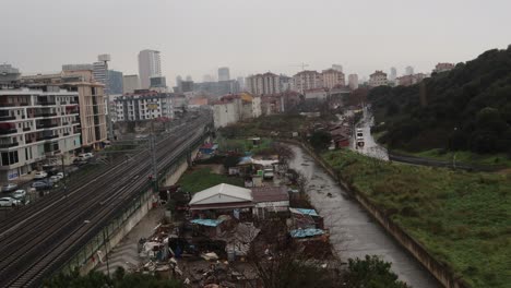 trains travelling on railway track along slums and apartment buildings near stream in maltepe district of istanbul, turkey