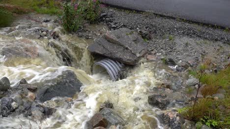 el agua de lluvia se precipita en la alcantarilla que corre debajo de la carretera durante las inundaciones en noruega