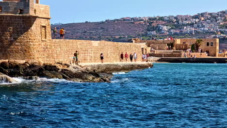 tourists at the venetian lighthouse in the old harbour of chania, crete island, greece. wide shot