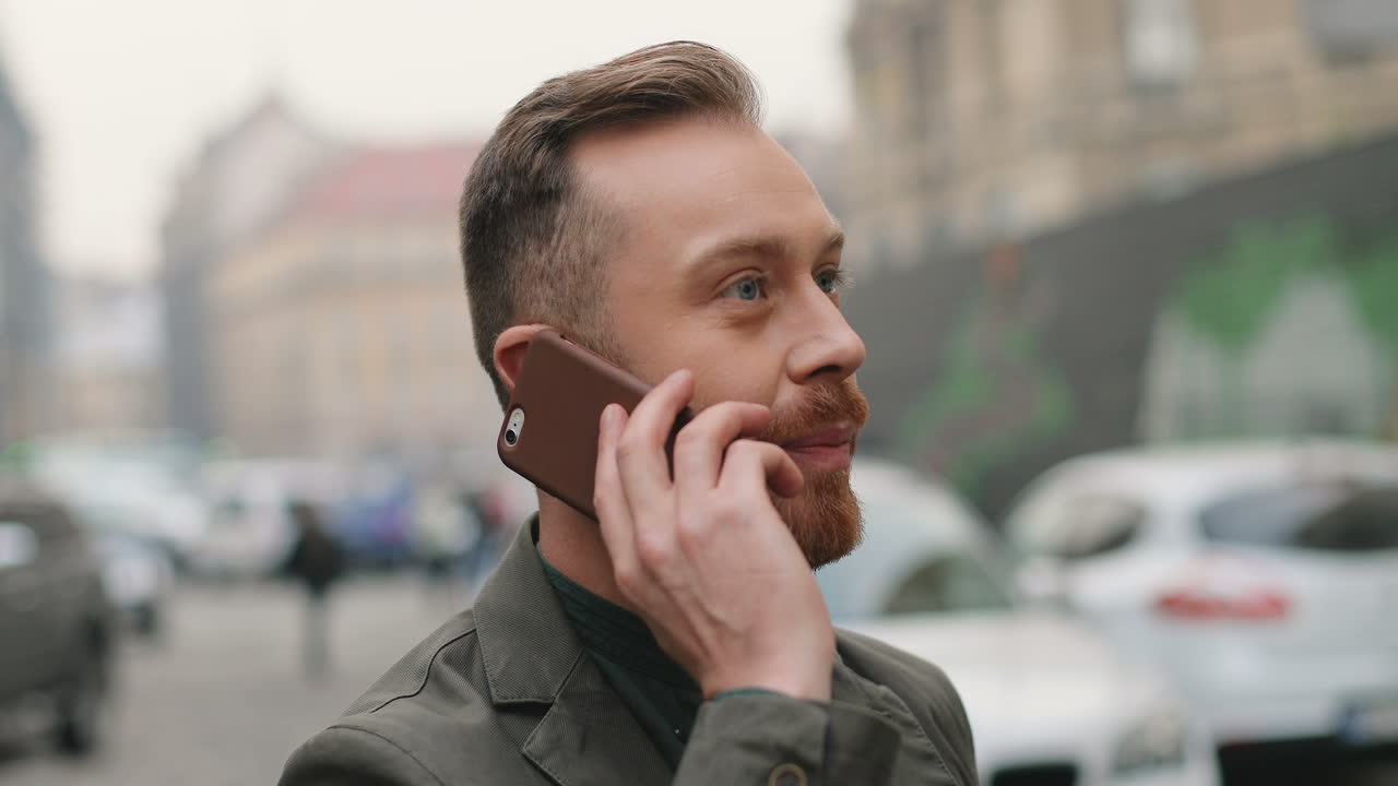 zbližný pohled na kaukazského usmívajícího se obchodníka, jak mluví po telefonu na ulici na podzim.