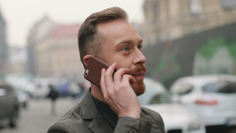 Close-up-view-of-caucasian-smiling-businessman-talking-on-the-phone-in-the-street-in-autumn