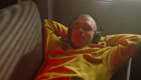 hombre relajándose en un sofá con auriculares