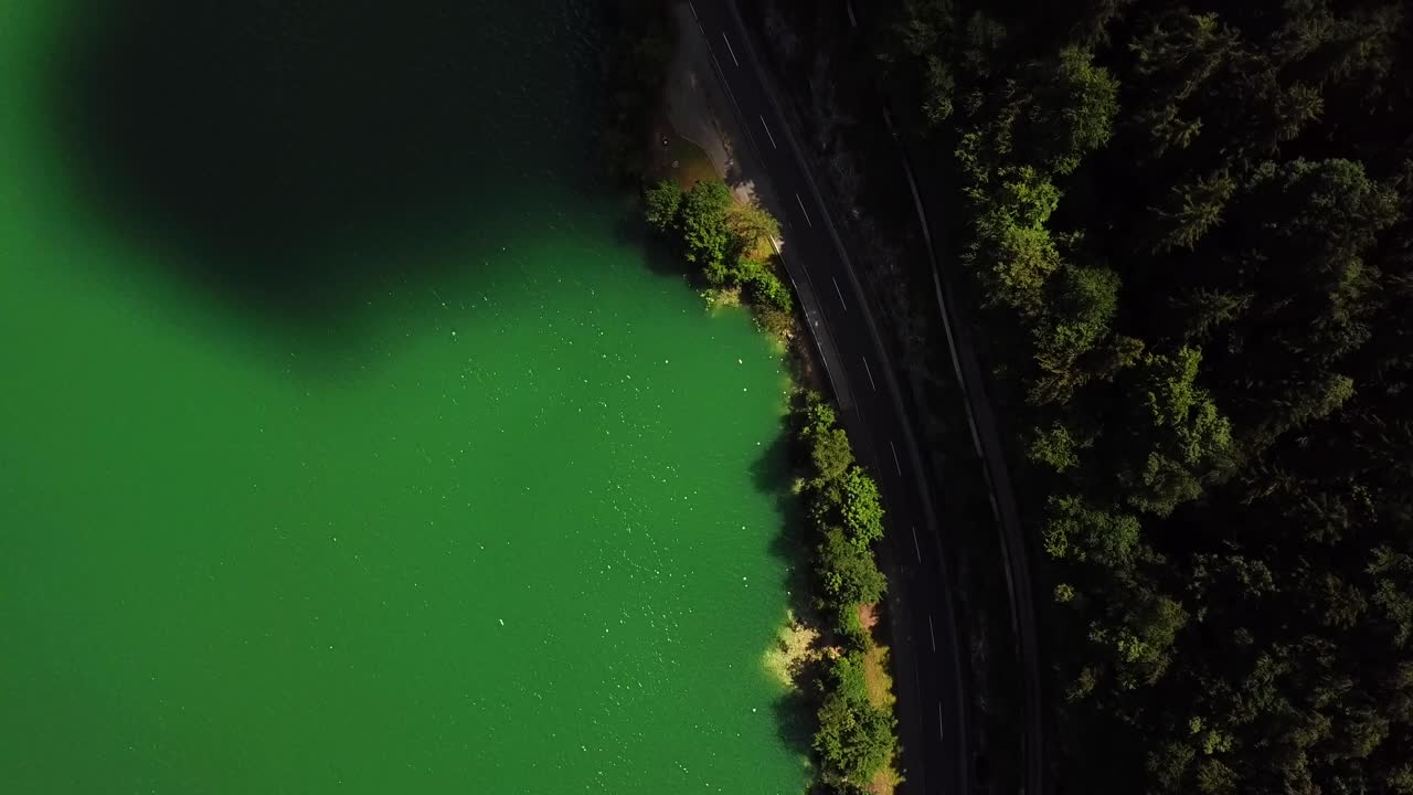 Aerial top view of a mountain road along the shoreline of lake Mondsee, Sankt Lorenz, Austria