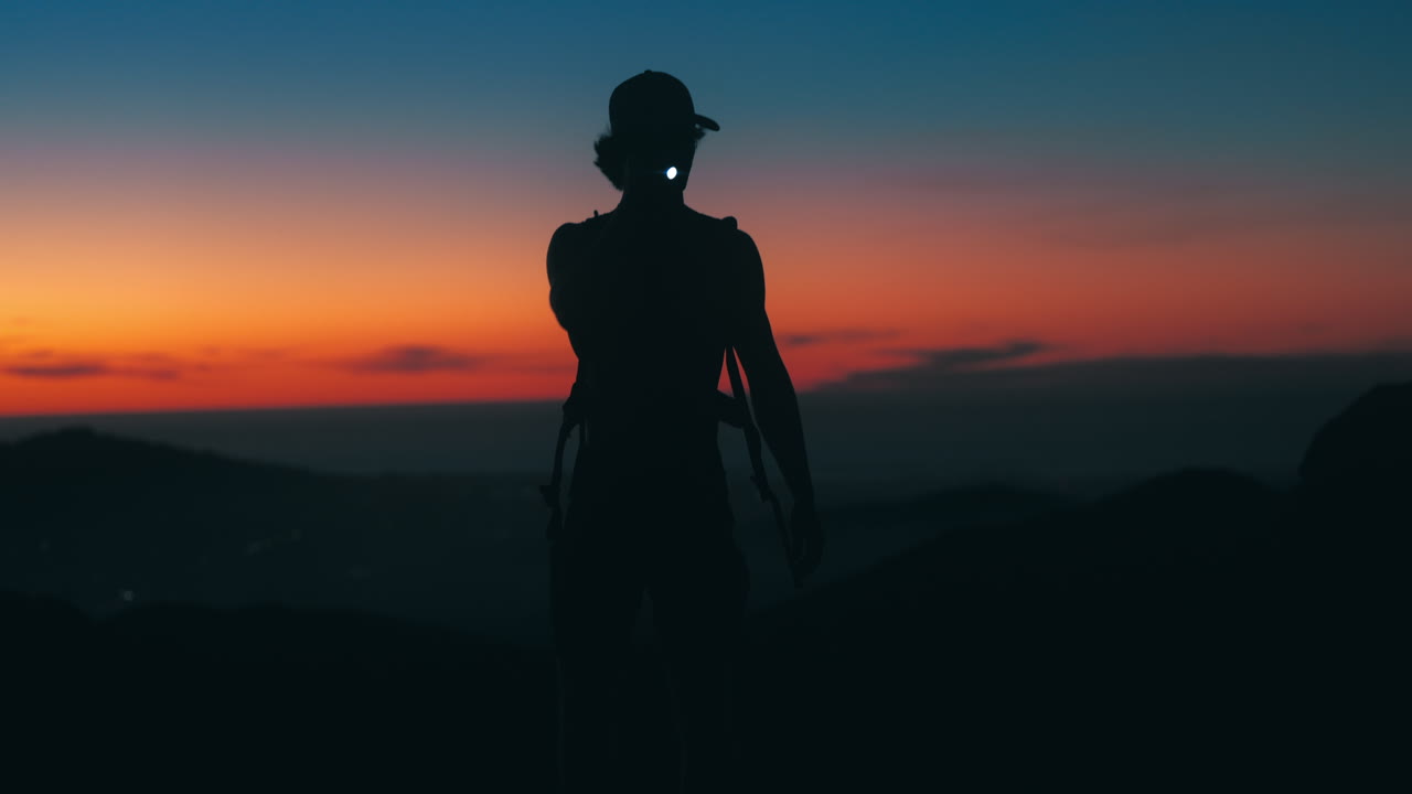 Man explores mountain top after sunset with flashlight. Shot on Canon R5 at 4k 24fps with RF 70-200mm f2.8 and chromatic flare fx filter.