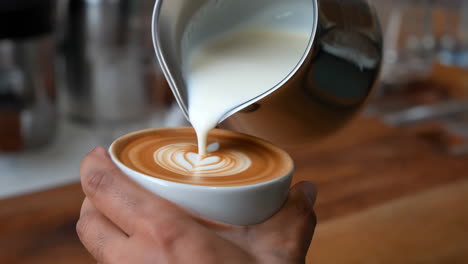 close-up of a barista pouring milk to create latte art
