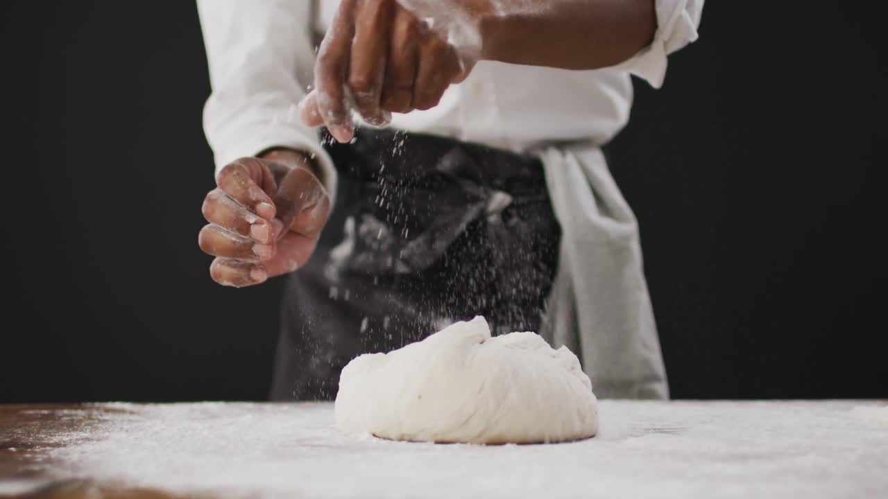 요리사 가 검은 배경 에 있는 테이블 에 밀가루 를 던지는 영상