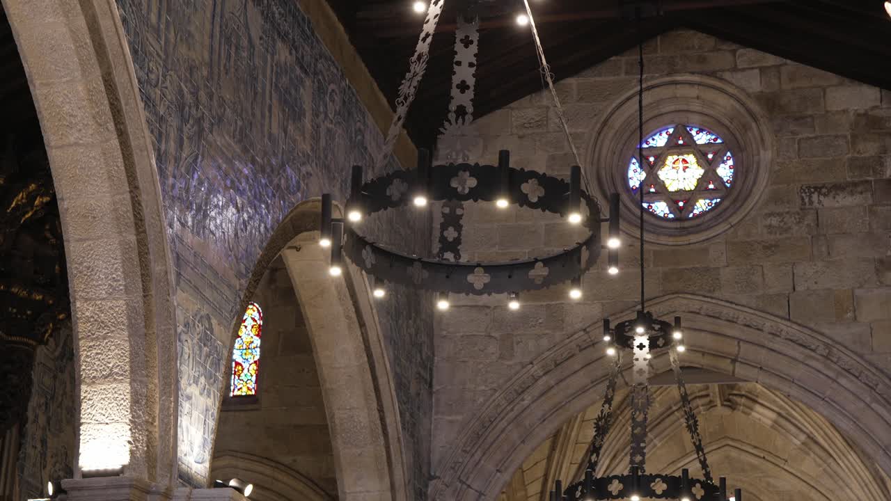 Interno di un'antica chiesa in pietra con lampadario gotico e vetrata a forma di stella.