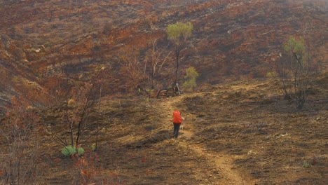 Excursionista-Sigue-El-Sendero-A-Través-De-Un-área-Rocosa-Dañada-Por-El-Fuego,-Australia-Central