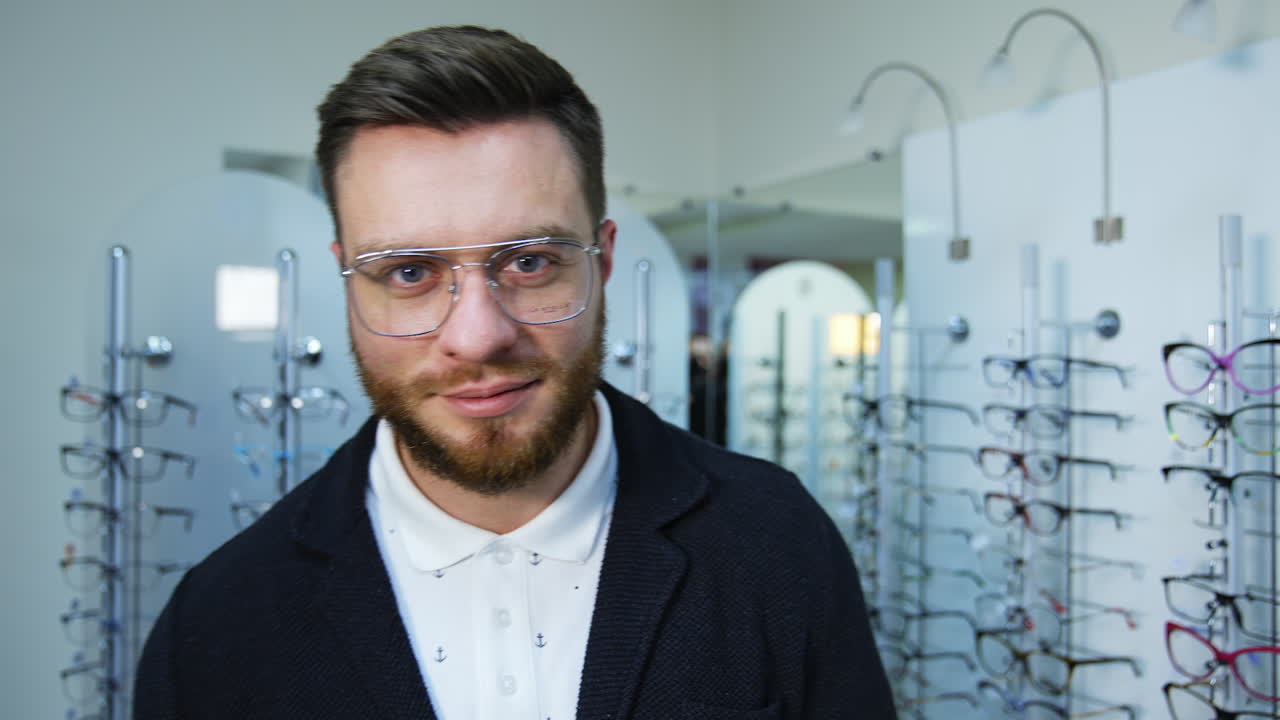 Male patient in optical store. Portrait of happy young man choosing new eyeglasses at optics store