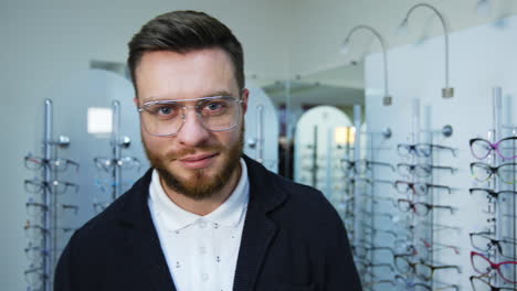male patient in optical store. portrait of happy young man choosing new eyeglasses at optics store