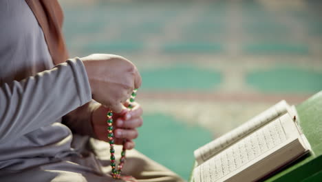 muslim woman reading the quran with prayer beads