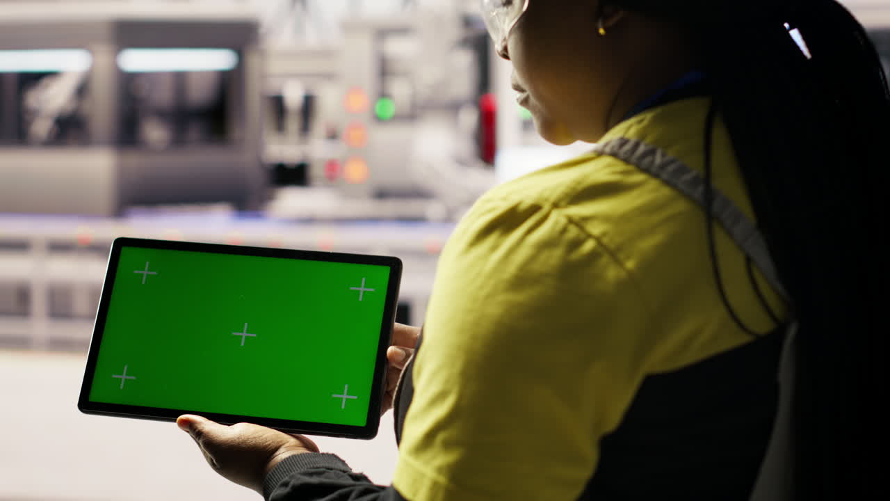 Smart factory specialist using green screen tablet to test automated systems