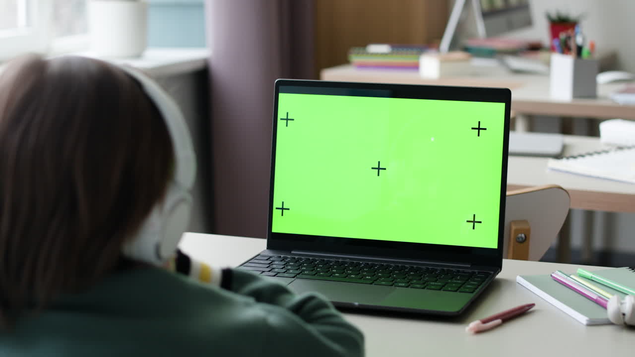 Student using laptop with green screen