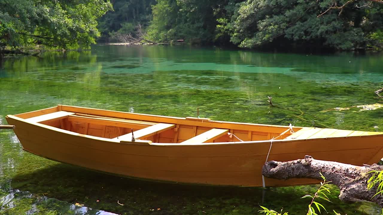bote pequeño de madera flotando en la superficie de un agua reflectante cristalina y tranquila