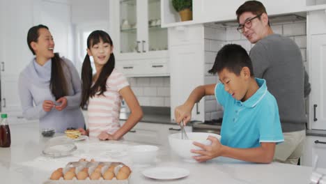 happy asian parents in kitchen with son and daughter, baking together